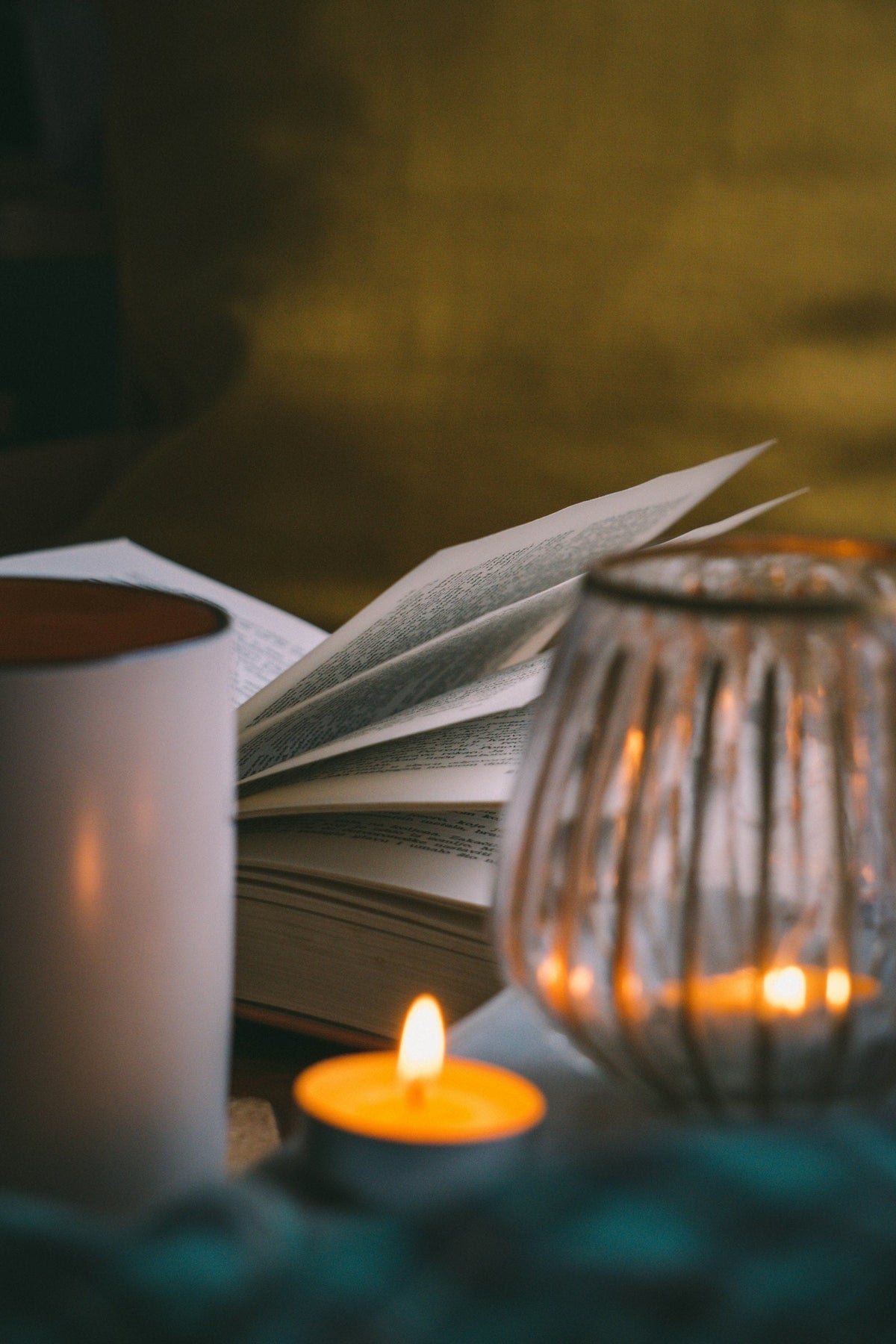 White pillar candle glowing in a glass holder